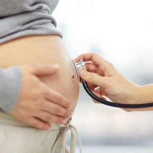 37679848 - Pregnancy, Healthcare, People And Medicine Concept - Close Up Of Pregnant Woman Belly And Doctor Hand With Stethoscope At Medical Appointment In Hospital